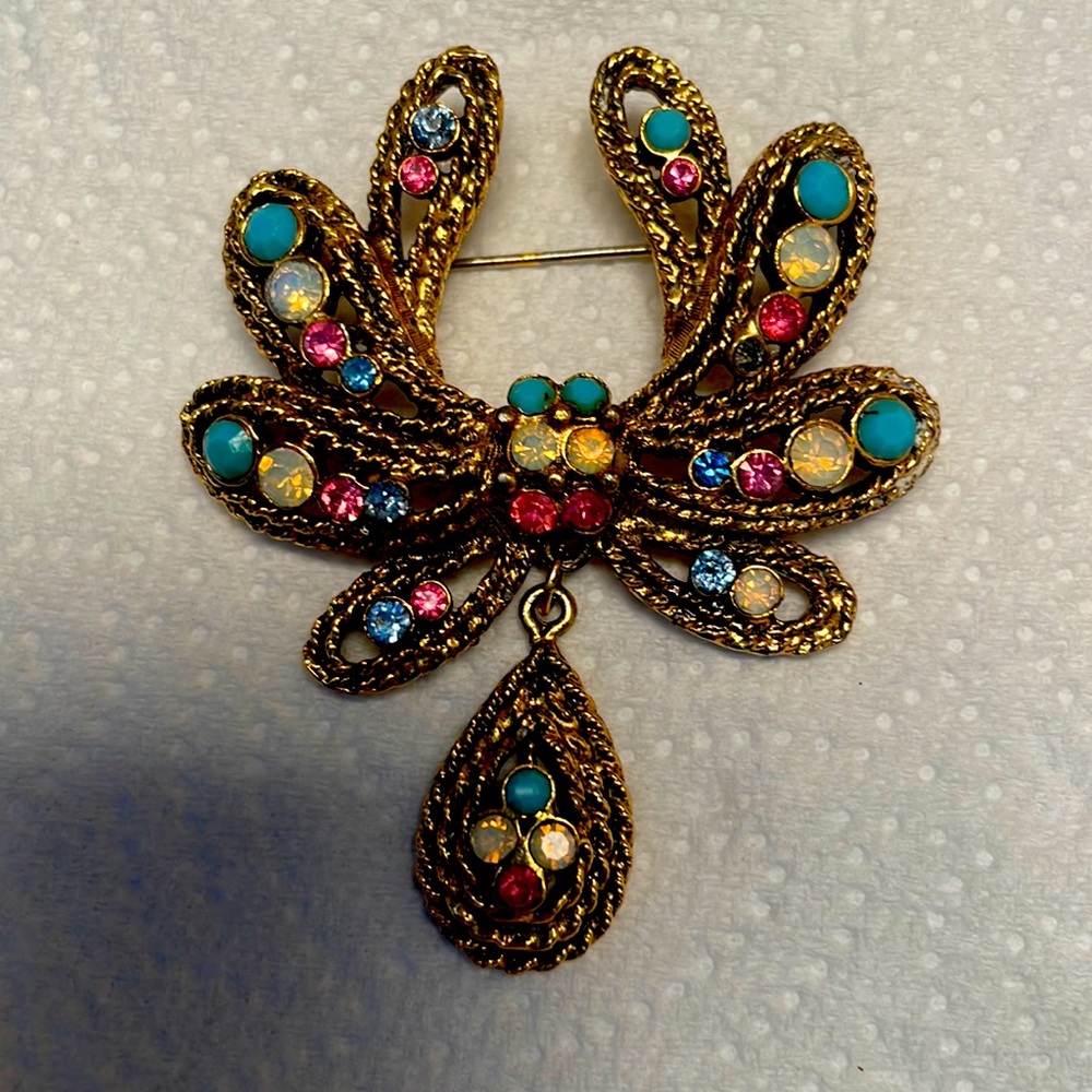 Gold tone, brooch with pink blue and white stones.